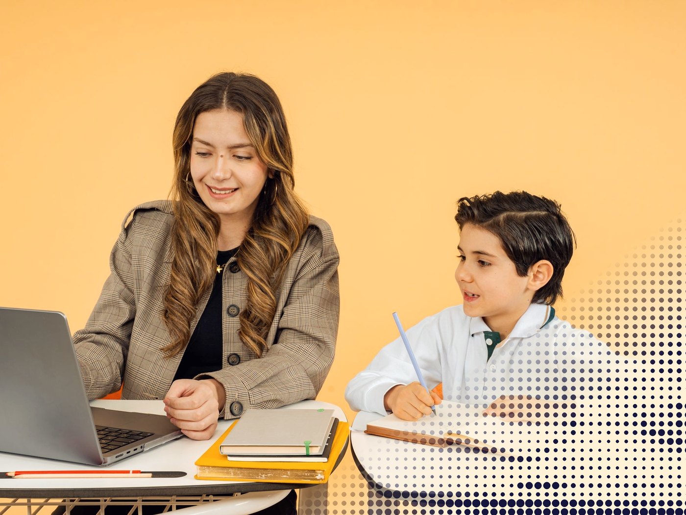 Docente trabajando en su computador junto a un estudiante