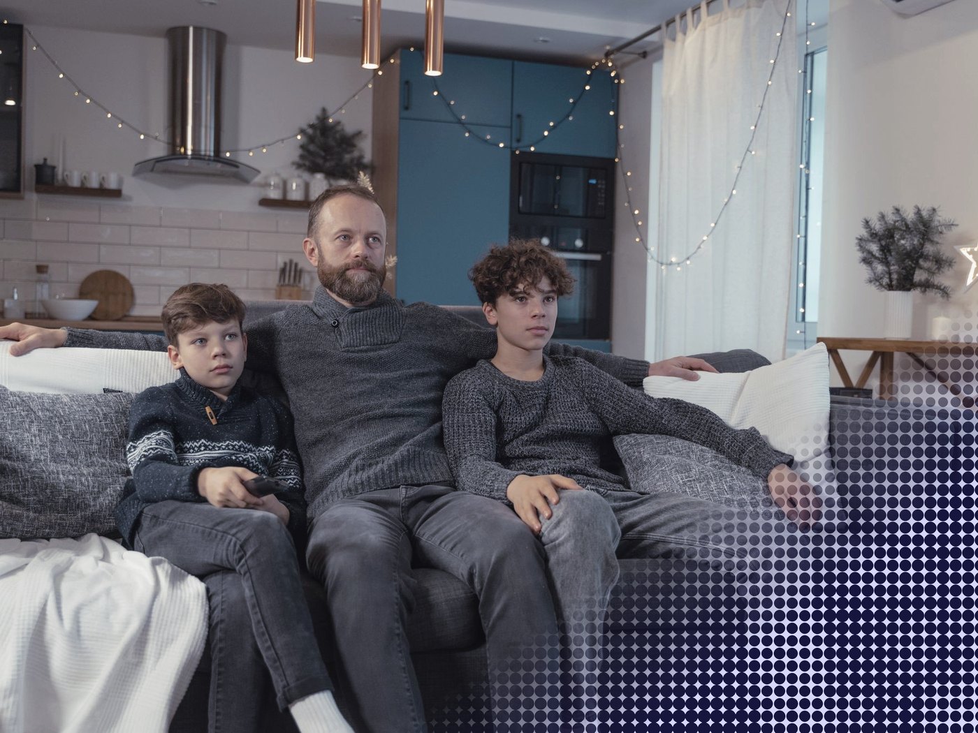 Padre y dos hijos mirando televisión en el sofá