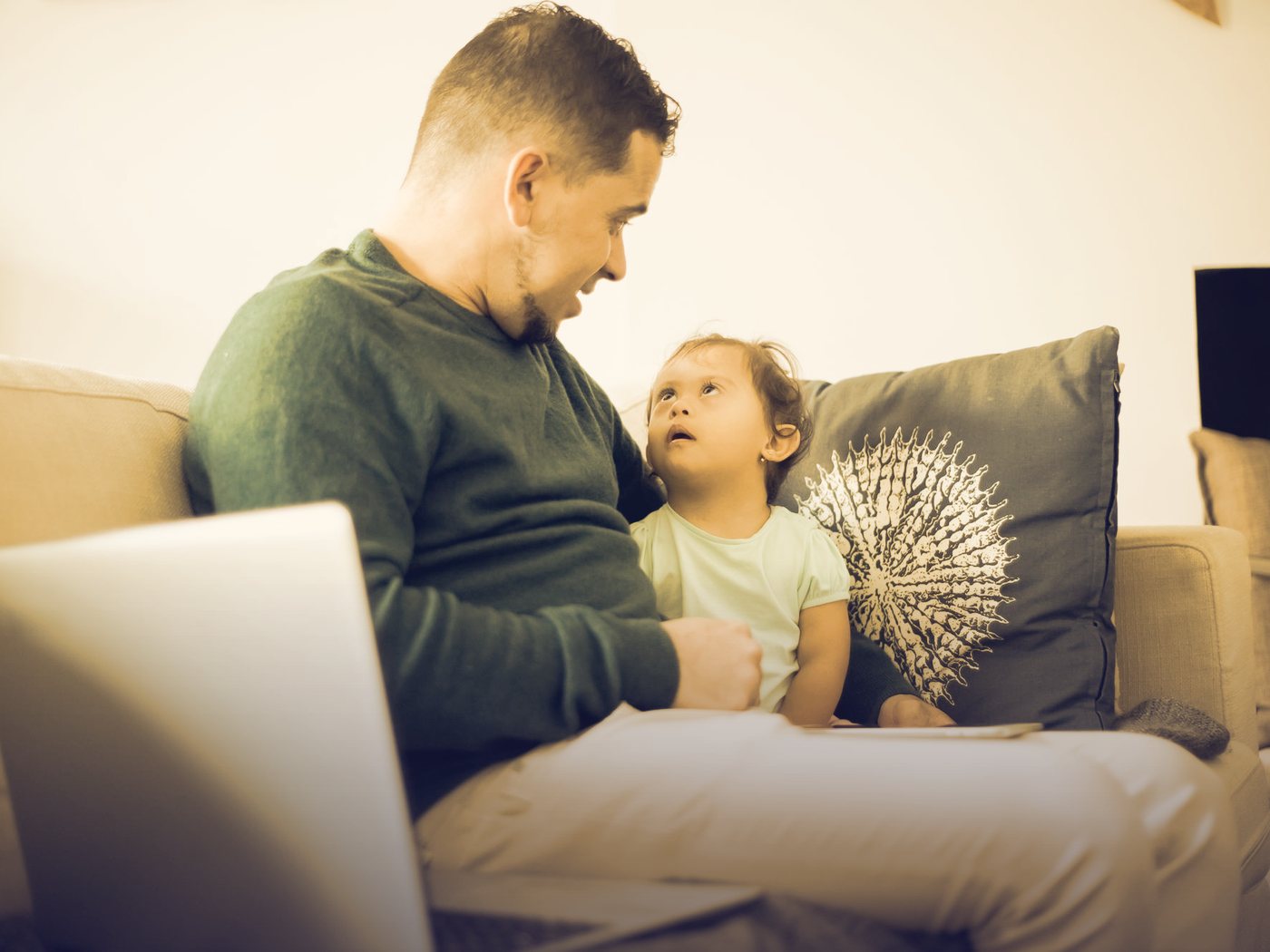 Padre con su computador mientras su hija lo mira