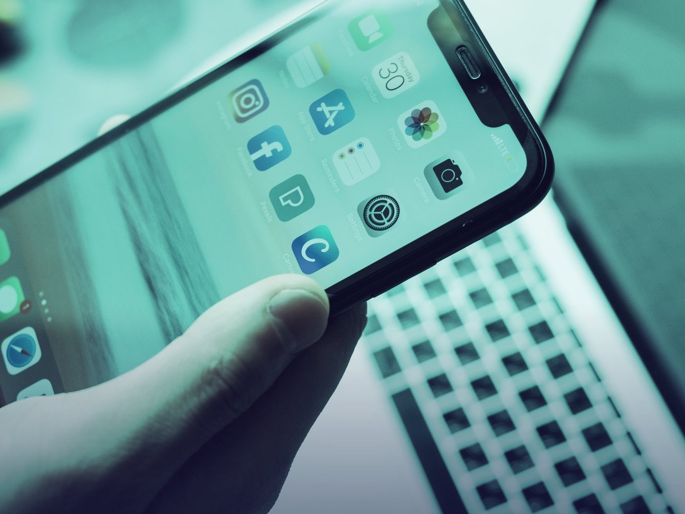 Mano sosteniendo un celular frente a un teclado