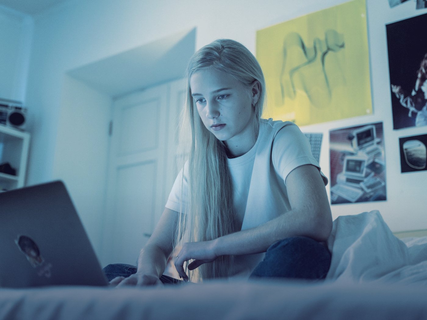 Estudiante trabajando con su computador en su pieza