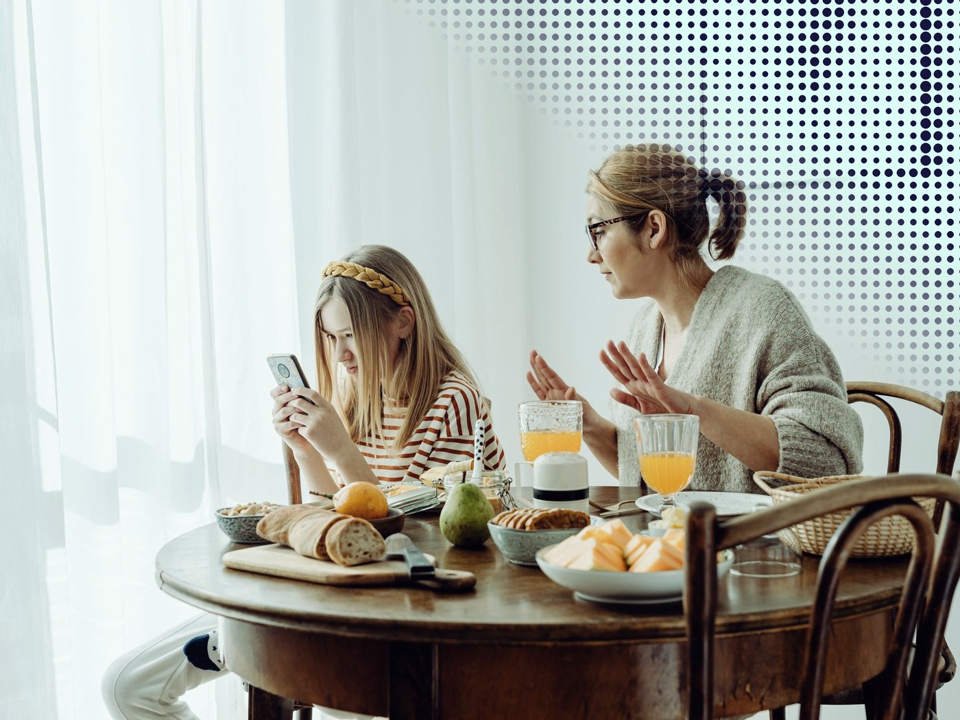 Madre e hija conversando en el desayuno, con el celular en la mesa
