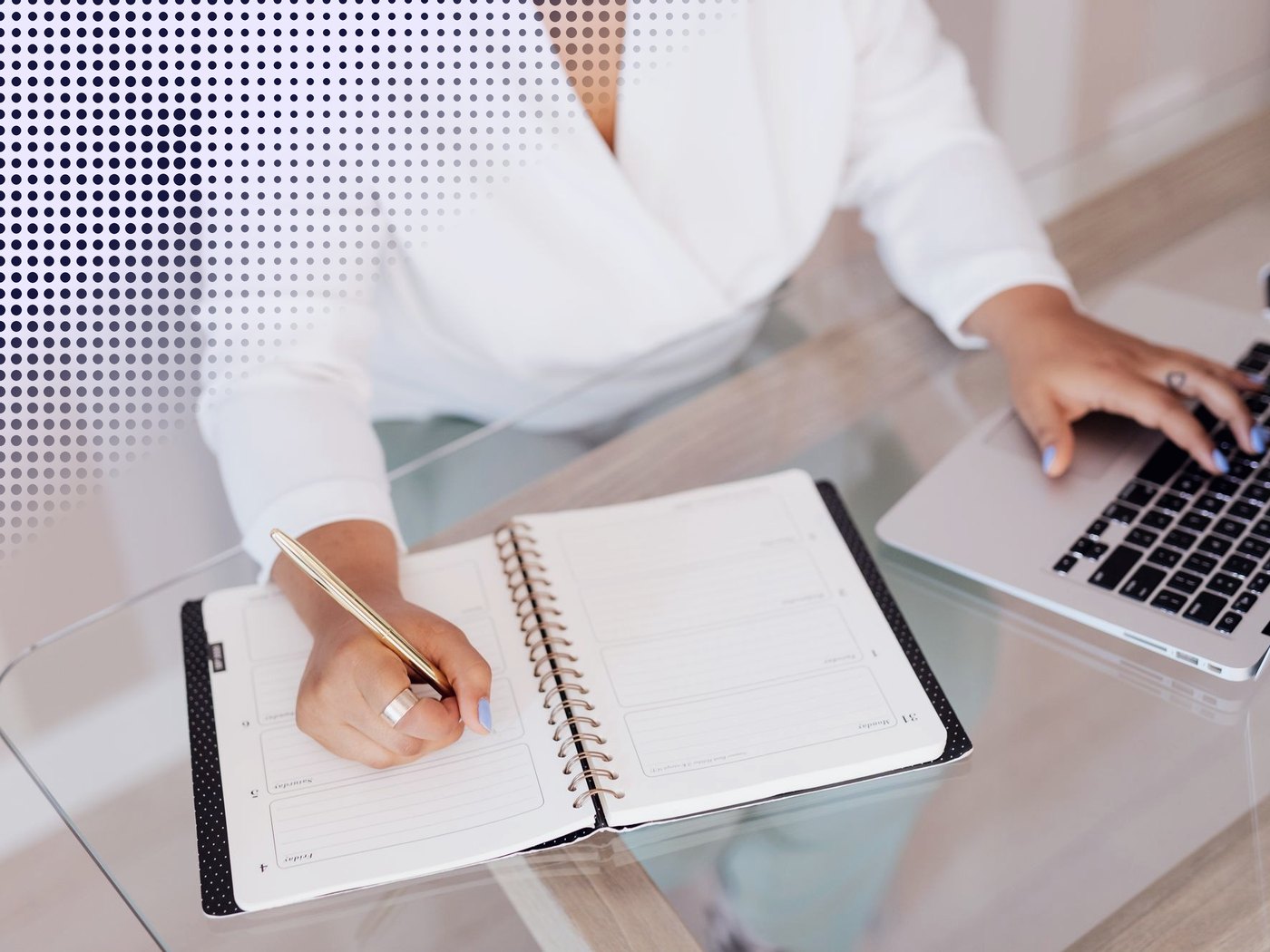 Manos anotando en una agenda junto a un notebook
